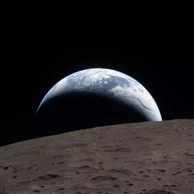 Vista de la Terra des de la superfície de la Lluna amb el paisatge lunar en primer terme i el planeta il·luminat a l’horitzó